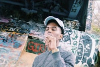 a man smoking a cigarette in front of graffiti