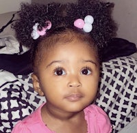 a little girl wearing a pink shirt and pink bows